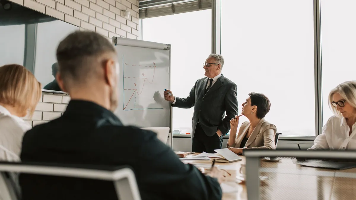 A senior leader presenting growth charts to colleagues in a meeting room