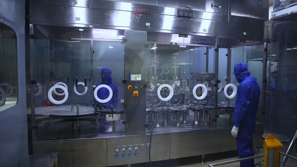 Operators in a pharmaceutical clean room beside filling equipment